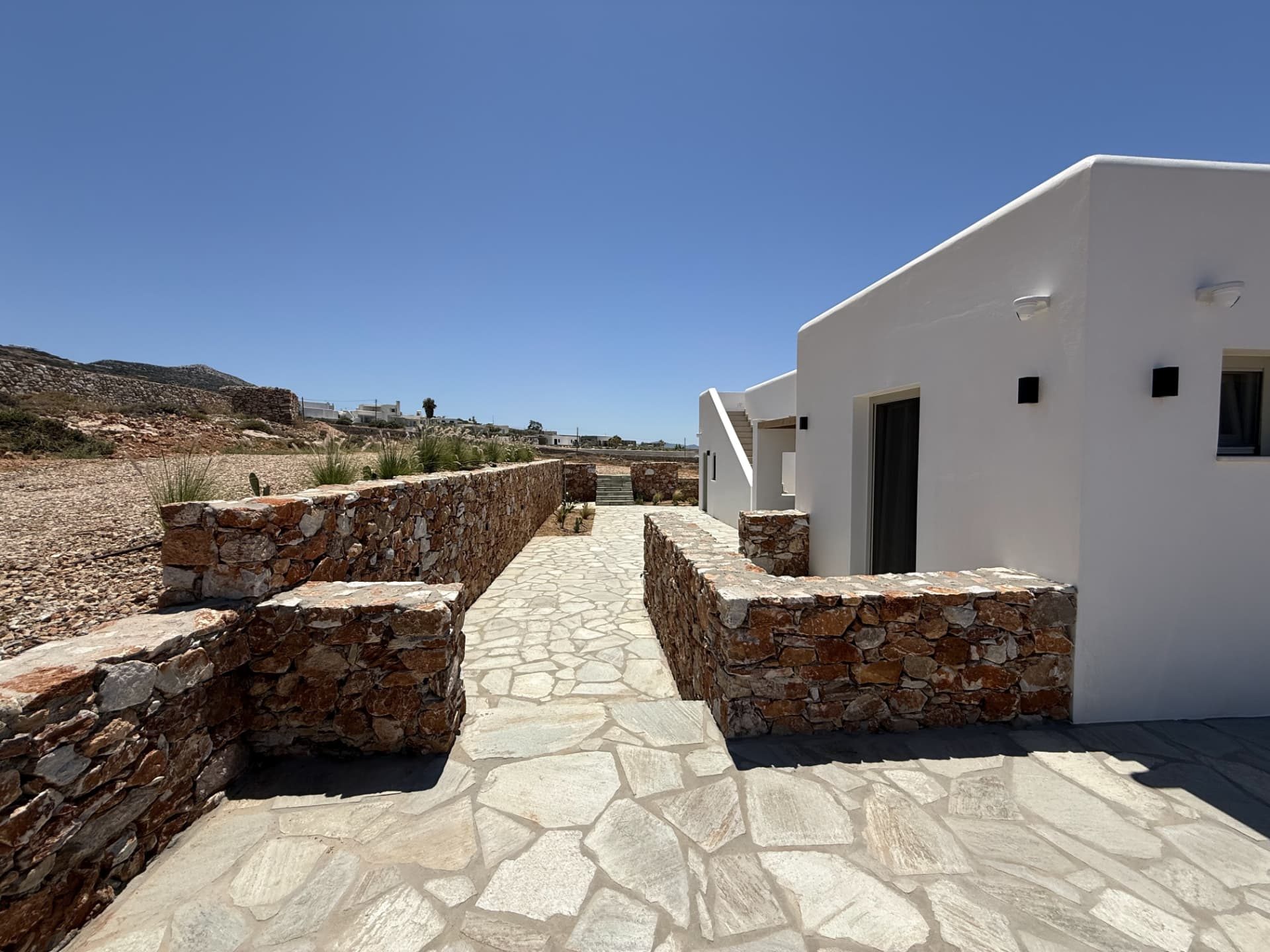 Dry-stone walls and flagstone paths leading to the entrance of DEON