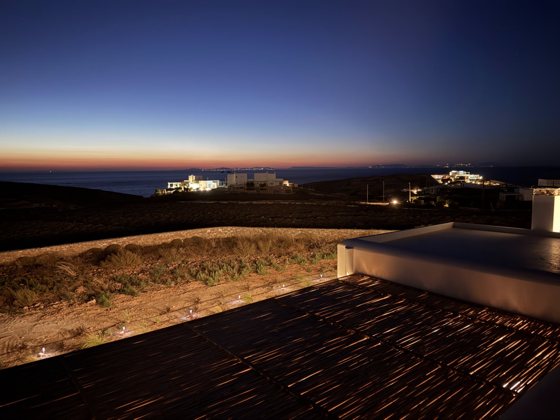 The gulf of Parikia at dusk seen from DEON, distant house lights along the coast